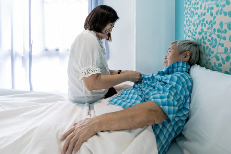 Assisting in dressing,female caregiver taking care of helping elderly patient get dress